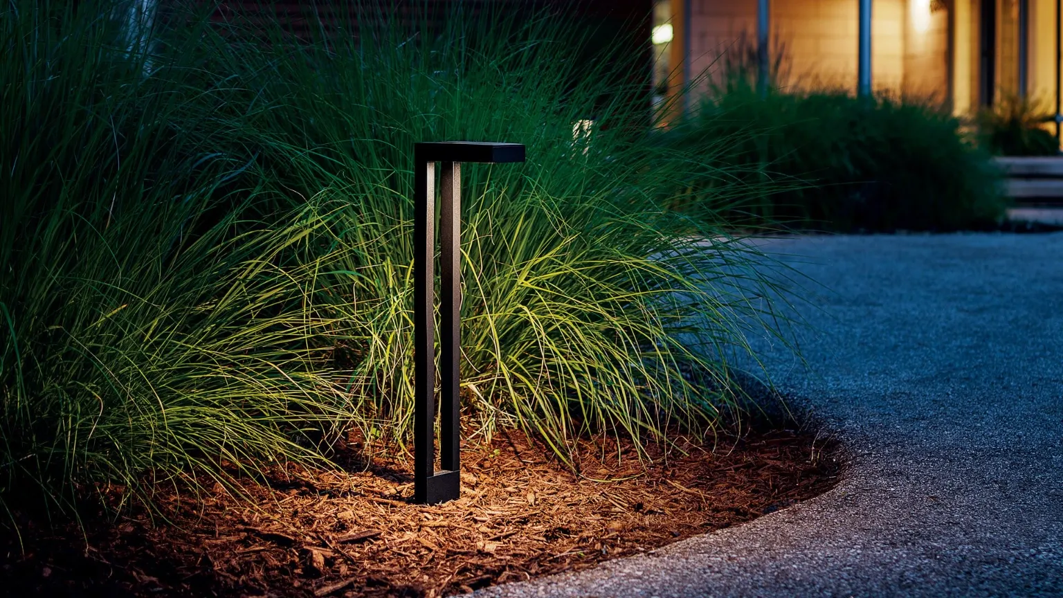 Modern path light beside ornamental grasses